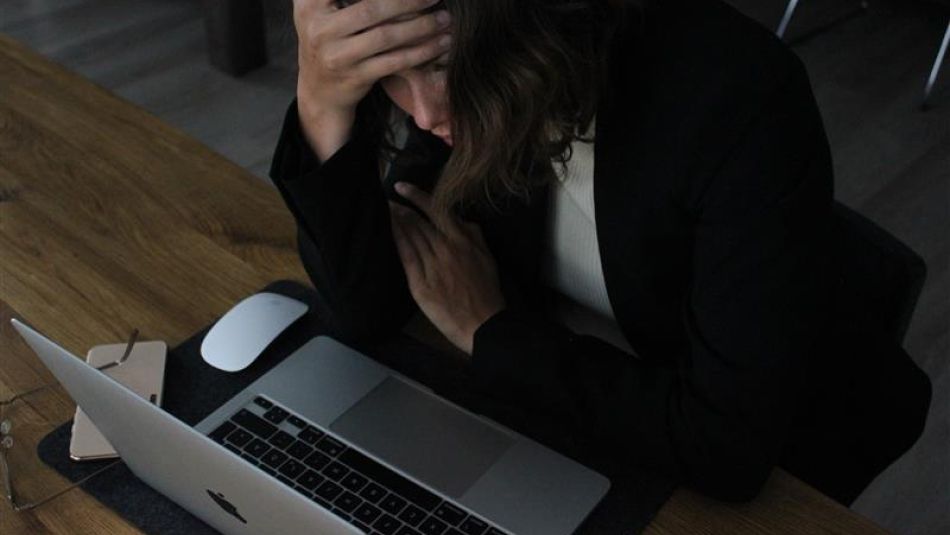 A women holding her head stressed looking over a laptop