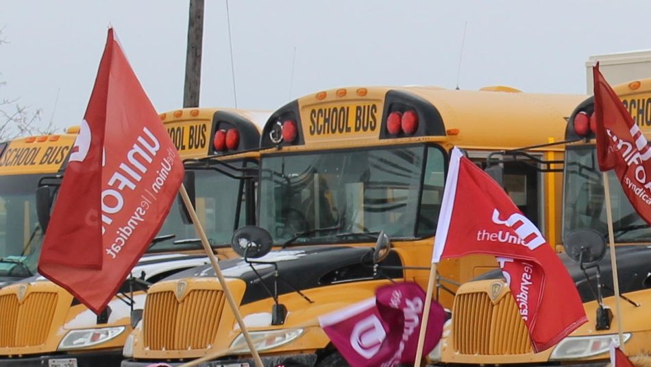 Bus scolaires garés avec le drapeau d'Unifor à l'avant 