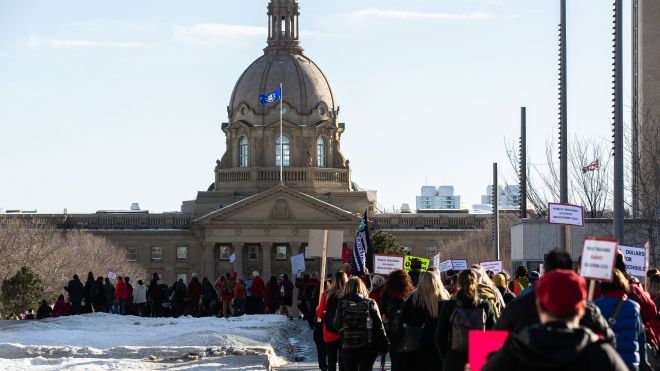 "Protestors marching towards the Alberta legislature in the distance."
