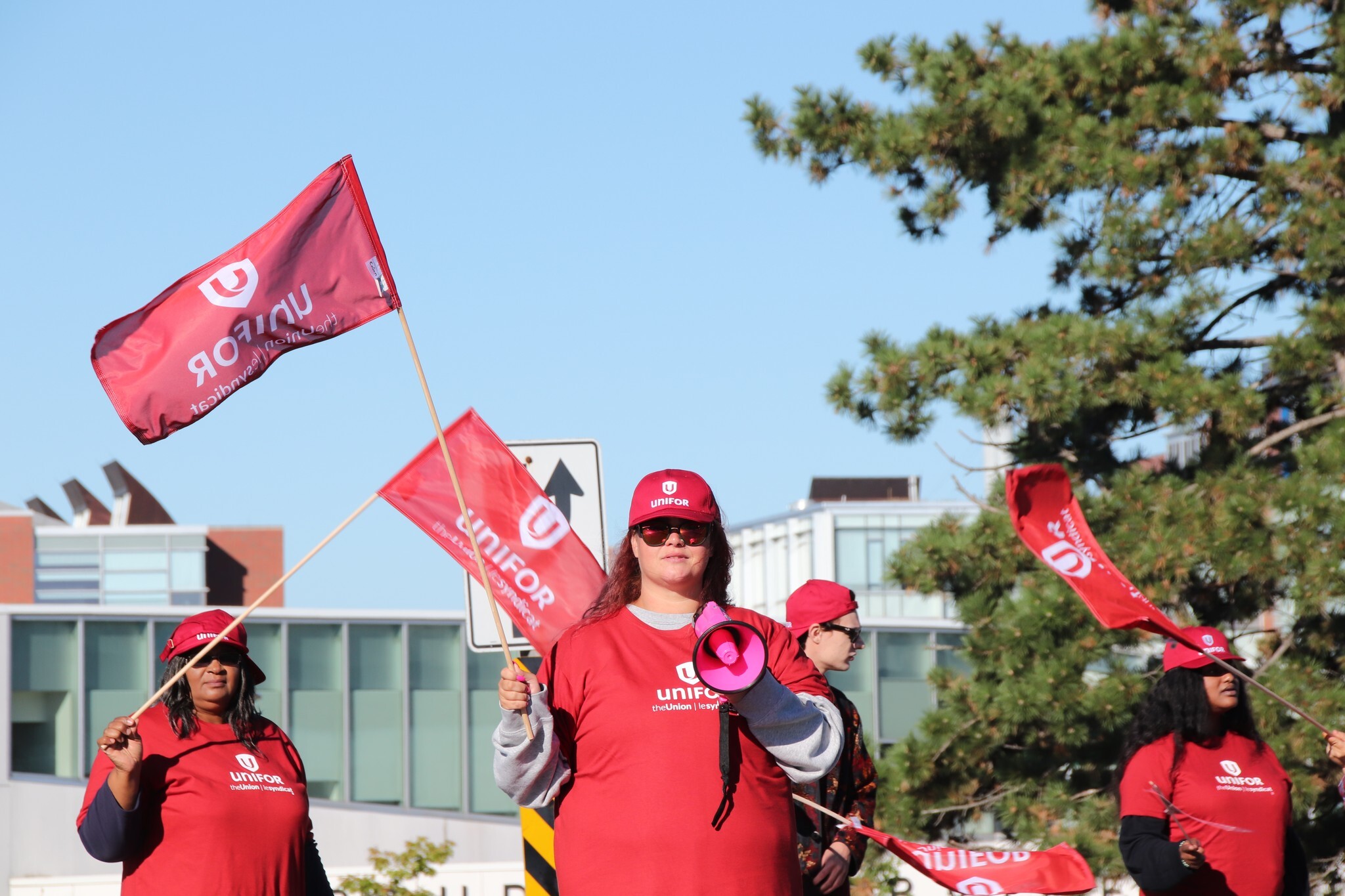 Members of GDI Services wearing Unifor t-shirts and holding flags and blowhorn 