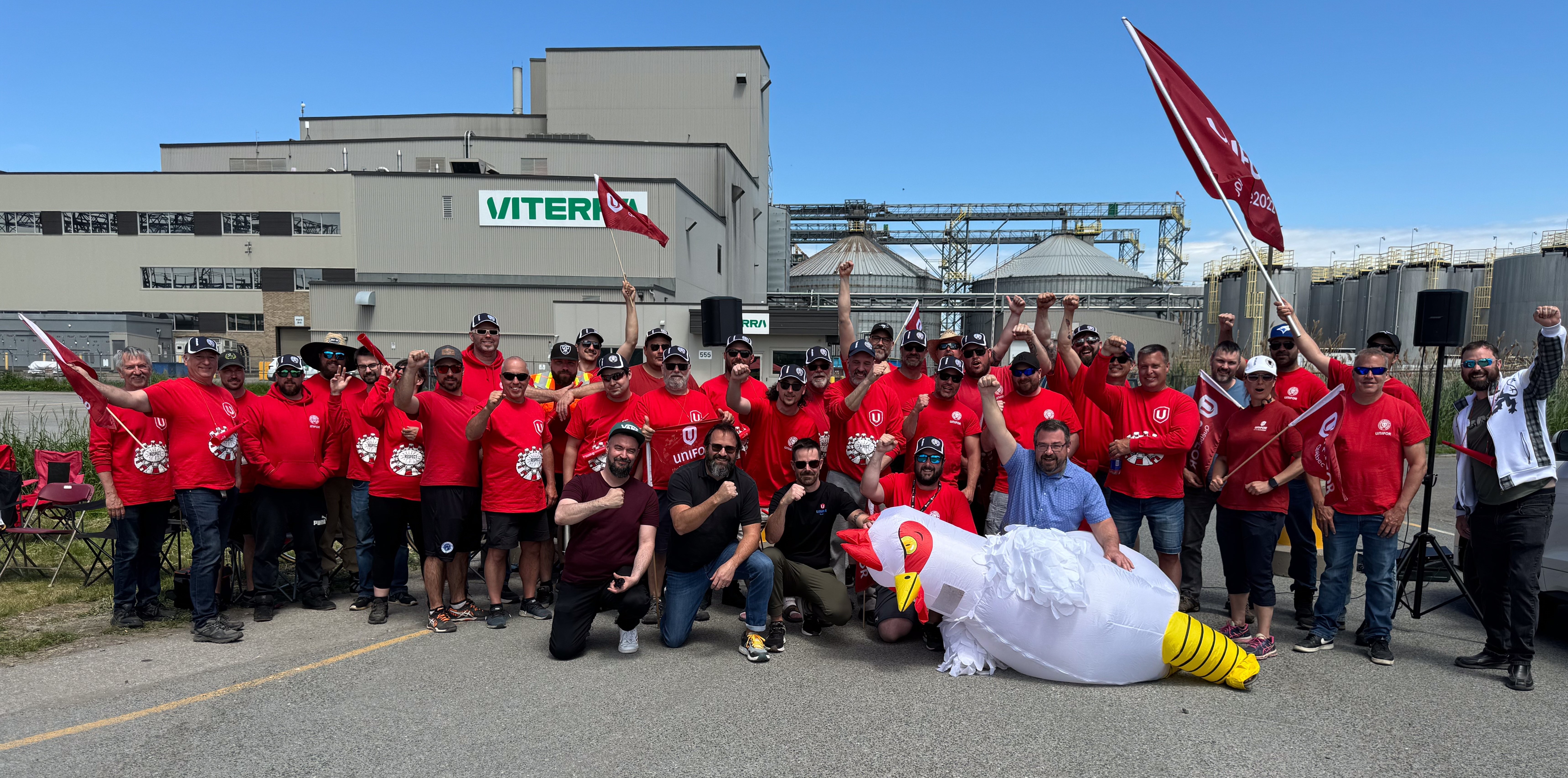 Viterra strikers posing in a group shot in front of the Viterra building with fists in the air and a person disguised as a chicken 