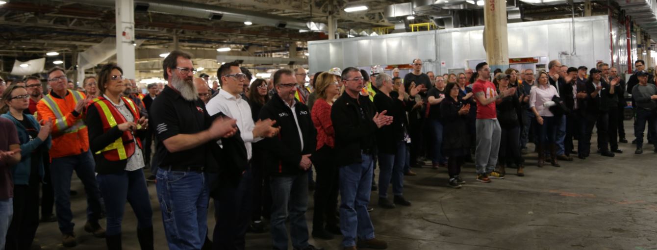 Hundreds of Local 222 members working at GM stand in the assembly plant applauding.