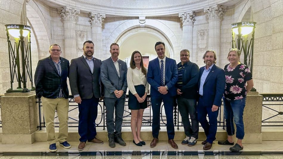 Eight people lined up inside the Manitoba legislature lobby for a photo