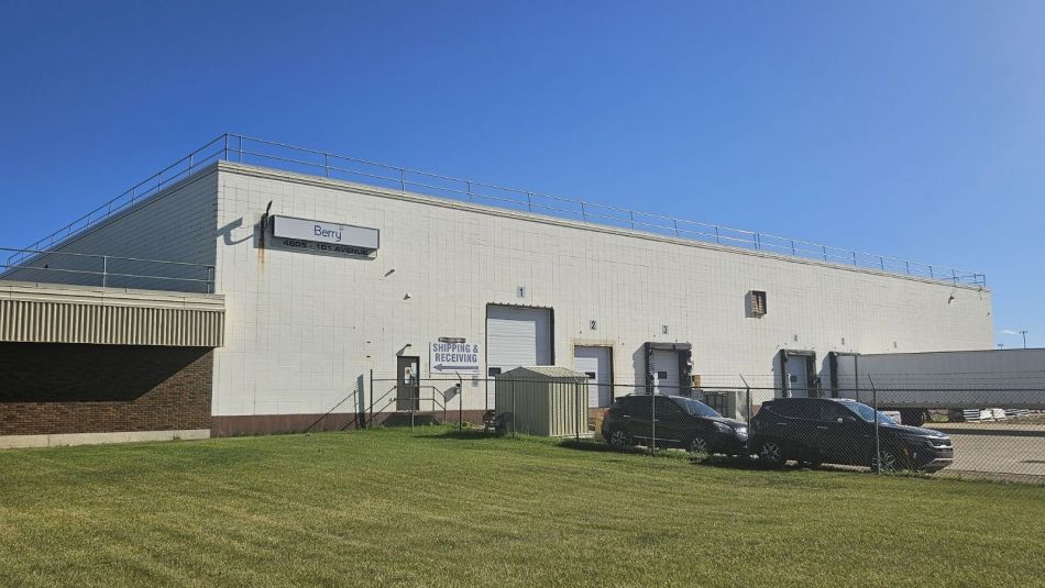 Alt text: Exterior of building with two vehicles parked in front of it.