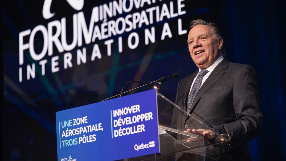 A man speaking at a podium in front of a large screen