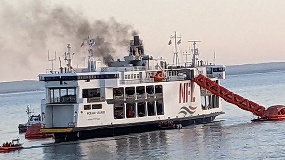 Black smoke billowing from the top of a Northumberland Ferry with emergency slides deployed.