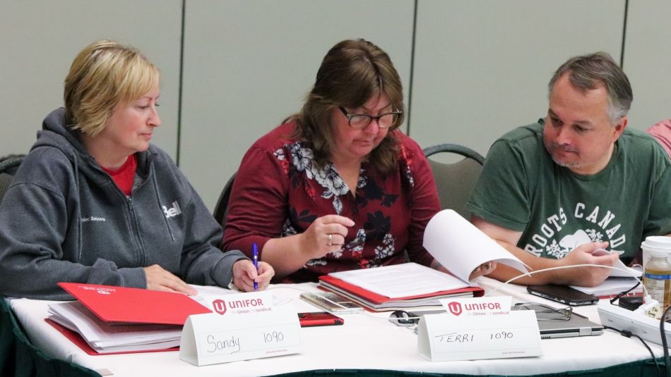 Three bargaining committee members seated at a table review documents together