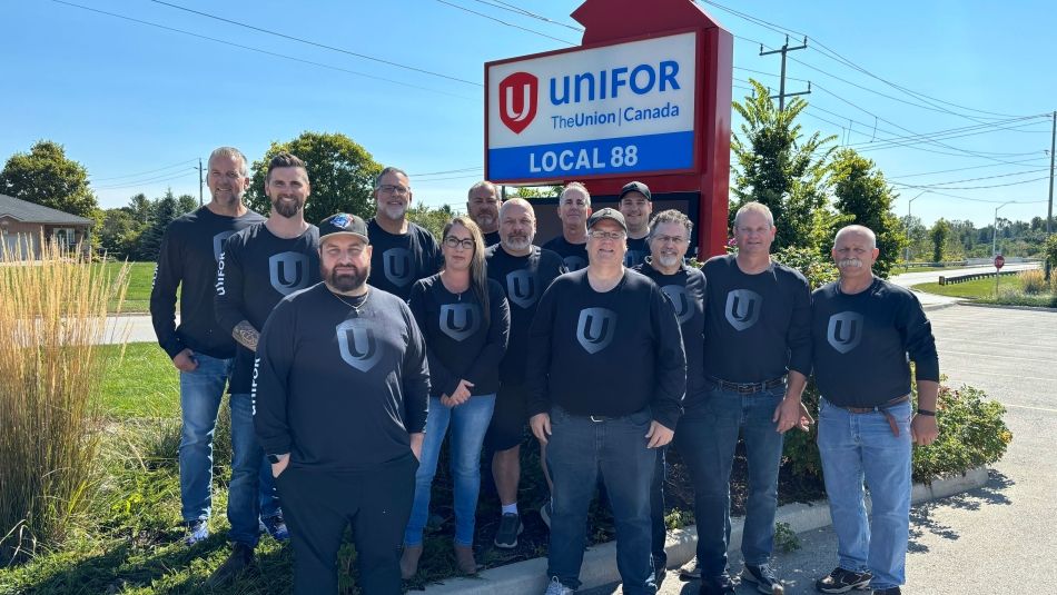 A large group of people wearing Unifor shirts standing outside in front of the Unifor Local 88 sign.