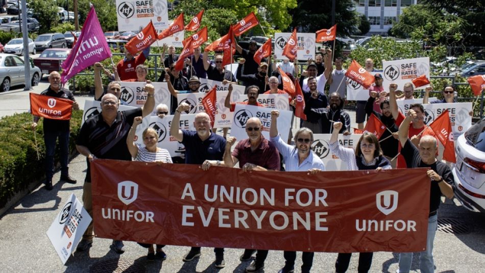 A large group standing behind a red banner that reads; Unifor a union for everyone