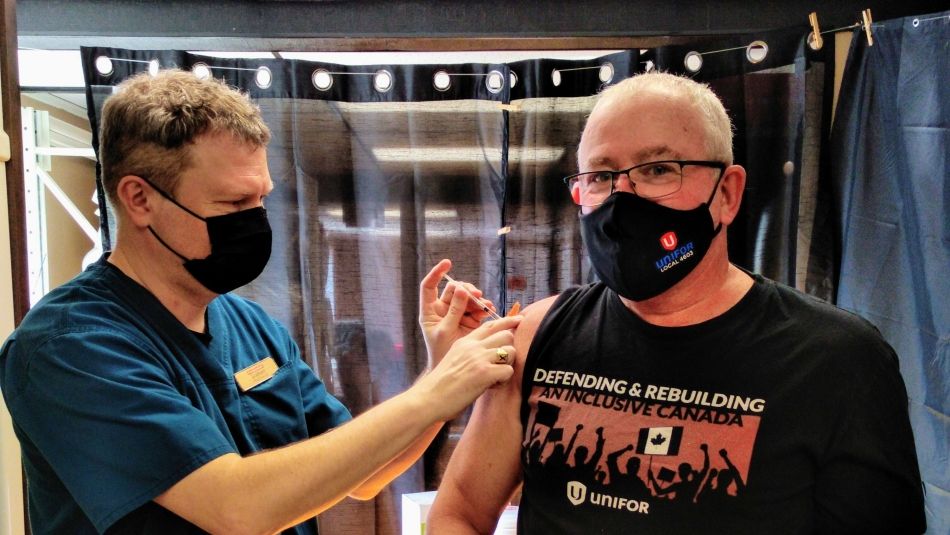 A Unifor member receives their COVID vaccine from a health care worker.