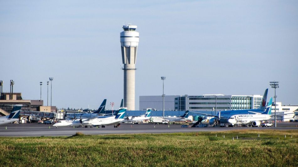 Airplanes on the tarmac with airport in the background.