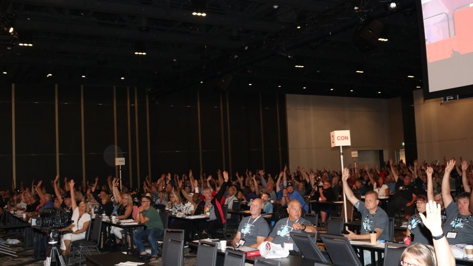 A room full of Canadian Council delegates raising their hands to vote on union business.