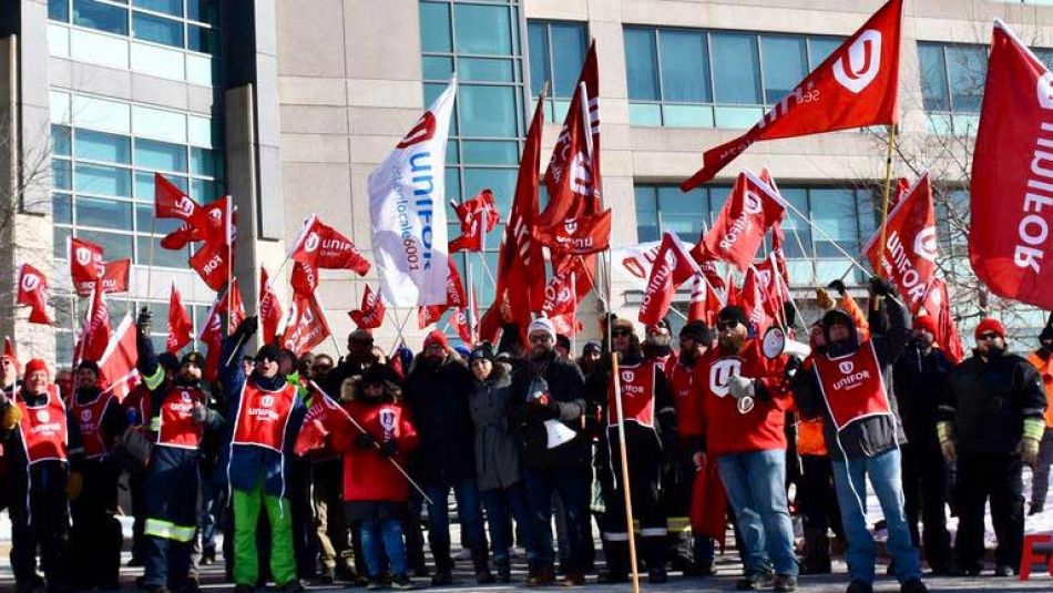 Unifor members wave flags at a rally.
