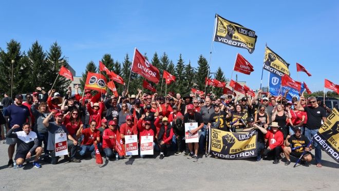 A group of people waving Unifor, PSAC and Videotron lockout flags