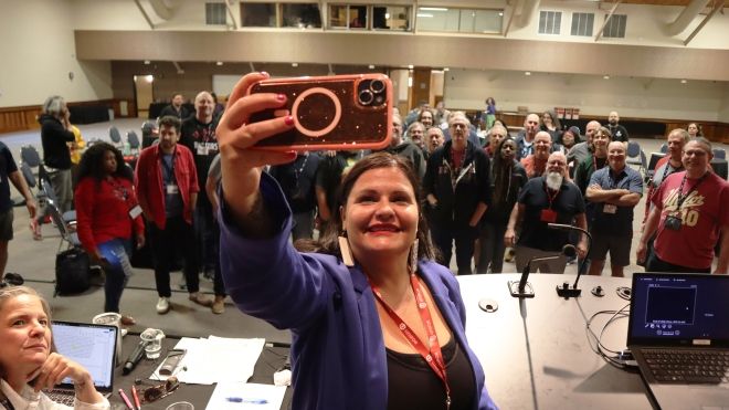 a women taking a selfie from a stage in front of a large group