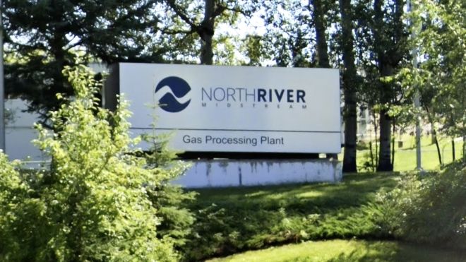 Outdoor signage amongst pine trees reading 'NorthRiver Midstream Gas Processing Plant