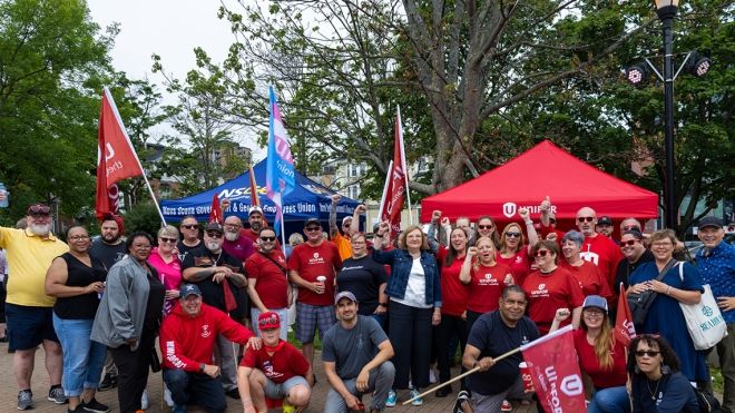 Unifor National President Lana Payne and Atlantic Regional Director Jennifer Murray surrounded by members in red shirts and holding Unifor flags at a rally.