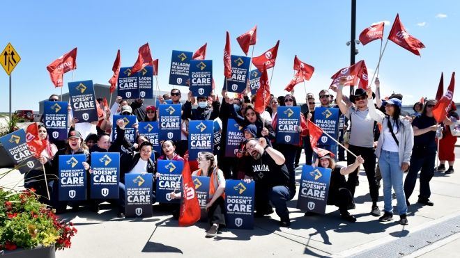 A group of people waving red Unifor flags and blue signs