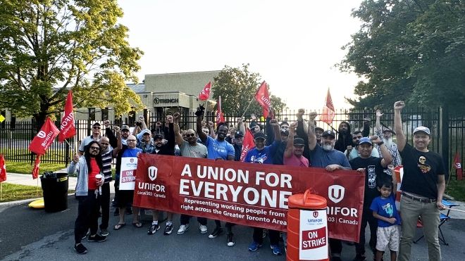 A group of people standing behind a red Unifor banner