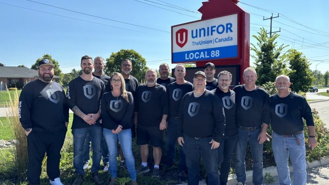 A group of people standing outside in front of a Unifor Local 88 sign