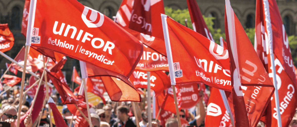 A crowd of people holding up red Unifor flags