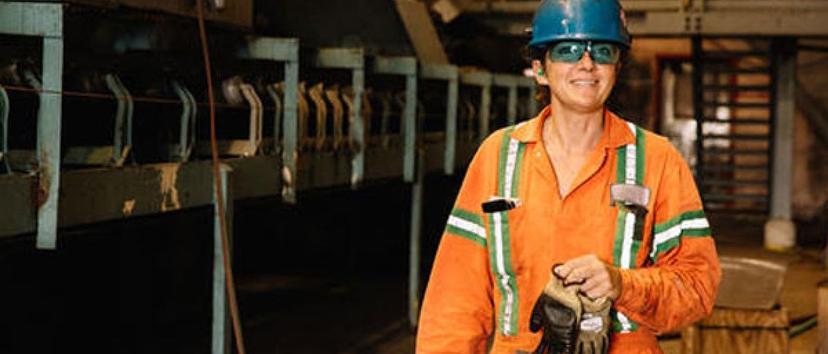 Trades women wearing a hard hat and orange overalls 